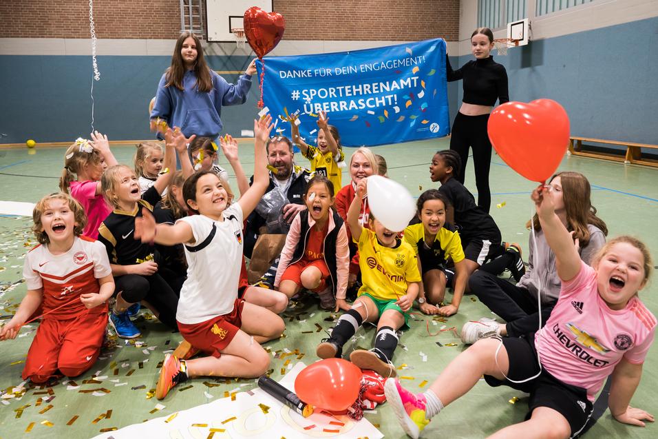 Gruppenszenen mit begeisterten Kindern in Sportkleidung, die Ballons halten und vor einem Danke-Schild feiern.